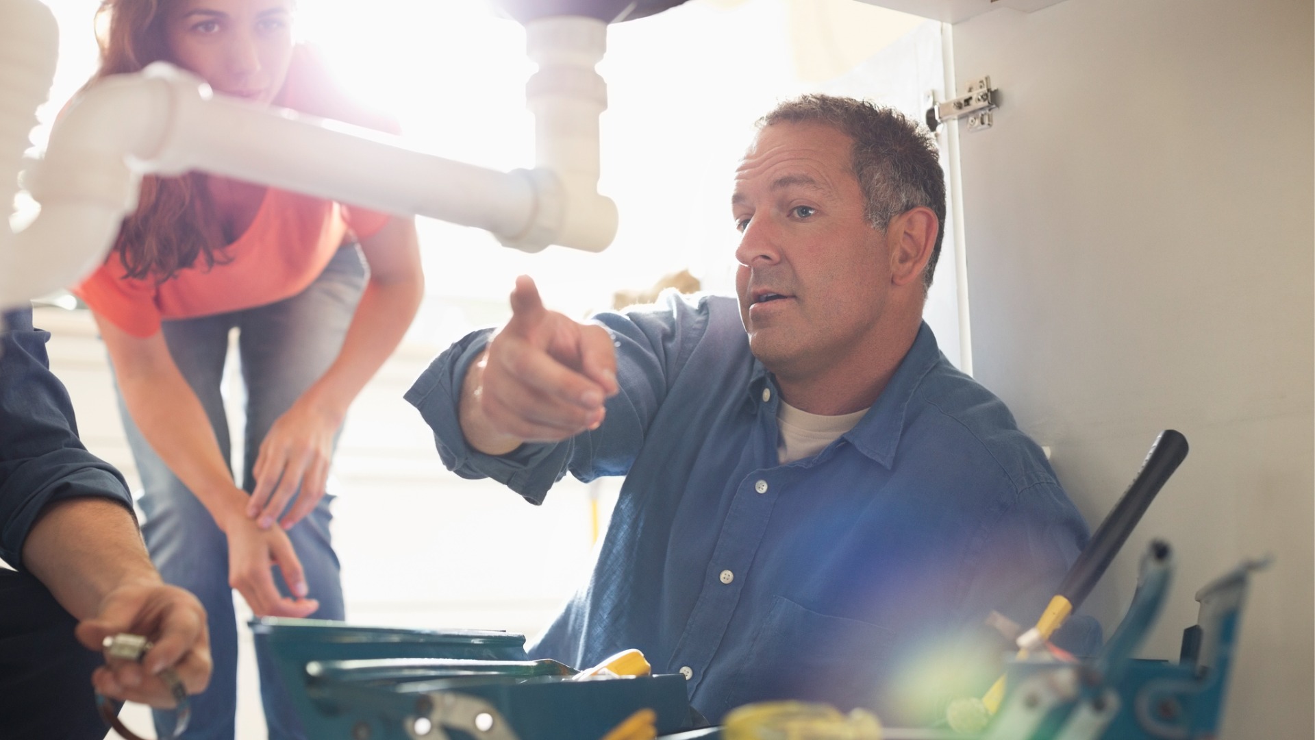 A plumber pointing to a leak under a sink while providing Residential Plumbing services in Peoria IL