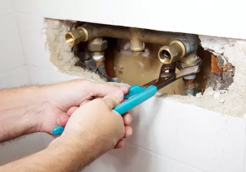 A man fixing a leak for a shower pipe connection during Plumbing Repair in Peoria IL