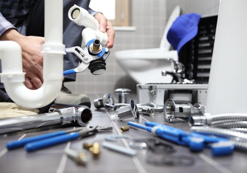 A plumber with tools and piping on the bathroom floor, as he performs repair for Residential Plumbing in Bloomington IL