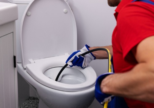 Plumbing contractors in Bloomington IL using a plumber snake to unclog a toilet