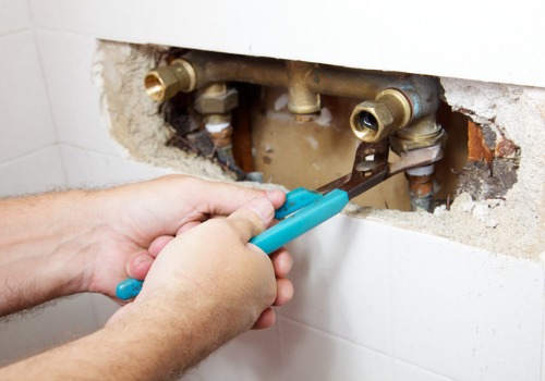 A man fixing a leak in a shower connection, as part of plumbing services in Bloomington IL