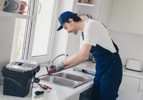 A plumber is seen working on a kitchen sink. TCI Plumbing performs Plumbing Repair in Peoria IL.