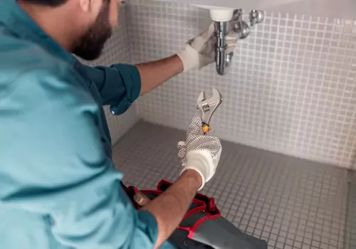 A plumber is seen working under a sink. TCI Plumbing are Plumbers in East Peoria IL