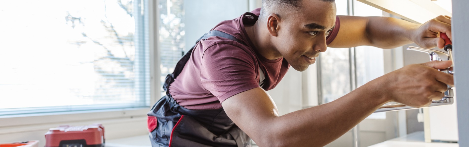 A plumber fixes a leak in the kitchen sink. TCI Plumbing offers residential plumbing services in Central Illinois.
