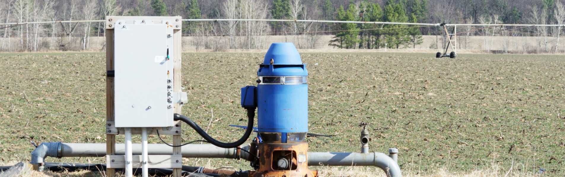 A Well and electrical panel with pivot irrigation system in the background is one of the water well and pump services options TCI Companies can tackle.