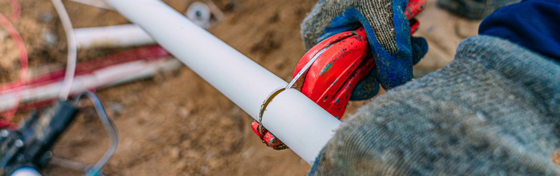 A team member from TCI Companies, a Decatur utility services company, cuts a PVC pipe to add a sprinkler line for irrigation to a home’s yard.
