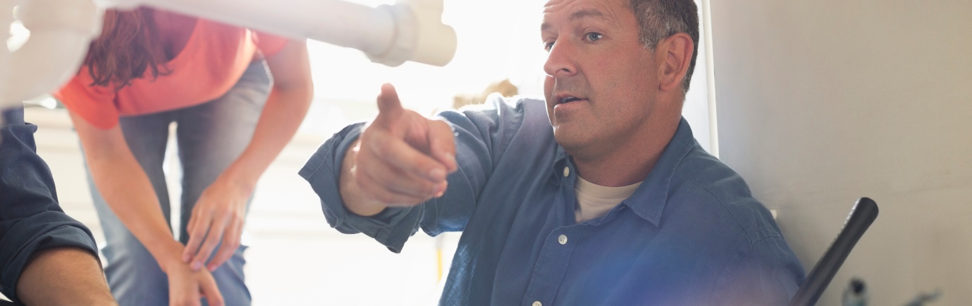 A plumber from TCI Companies, a local Bloomington utility services company, shows a couple what’s wrong with their sink plumbing.